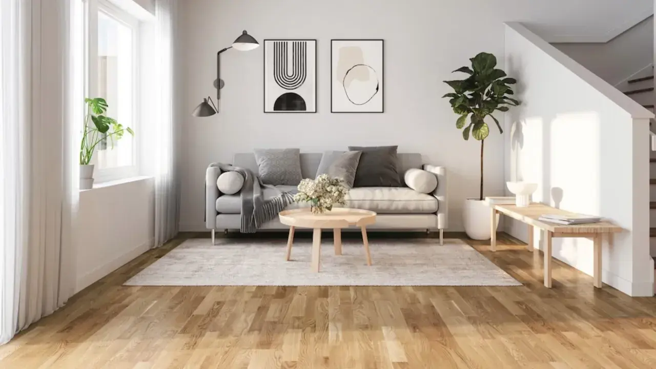 Ljust vardagsrum med grå soffa, runt soffbord och en matta. Golvet är ett vackert laminatgolv med en naturlig träkänsla, där laminatgolv tjocklek bidrar till dess robusthet.