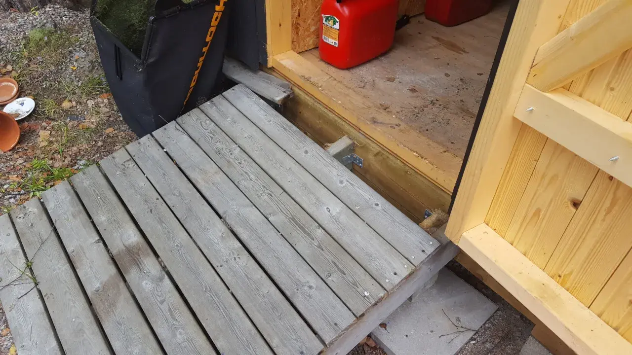 En nybyggd ramp till trappan gör det enklare att komma in i boden. En röd dunk står redo.