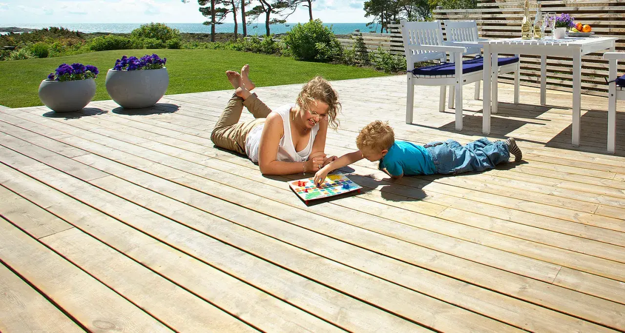 Kvinna och barn spelar spel på en altan med trall tjocklek som ger en stabil yta.