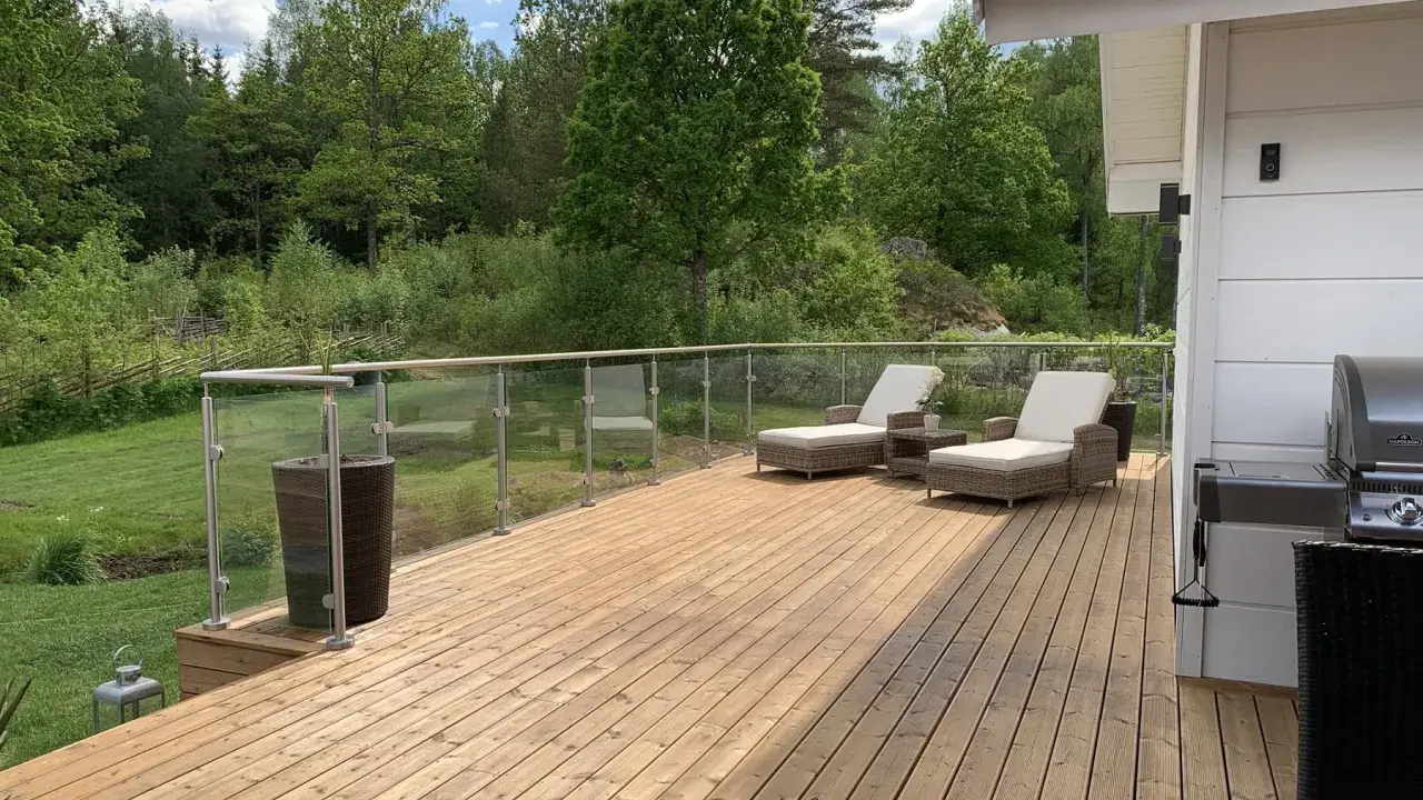 En nybehandlad altan med solstolar och grill, redo för sommarens mys. Snart dags att måla altan för att skydda träet.