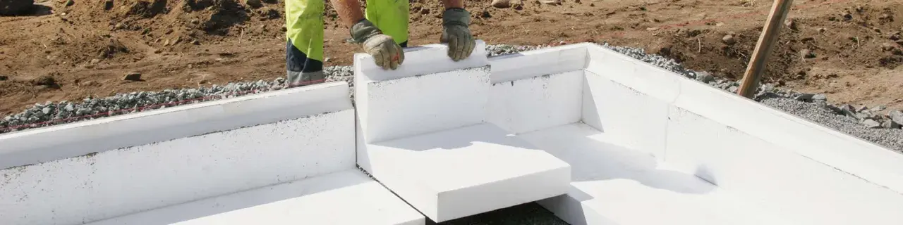 Arbetare lägger isoleringsblock för att gjuta grunden till ett hus.