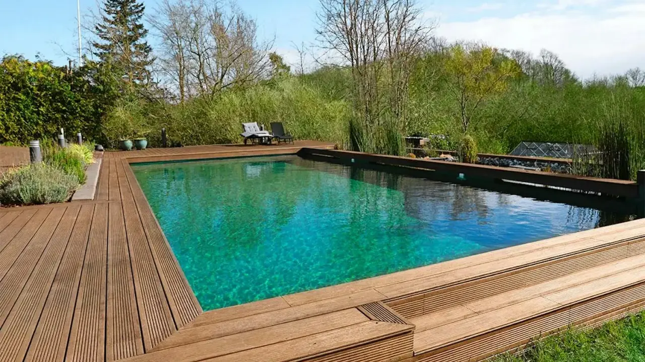 En vacker klorfri pool med trädäck och grönskande omgivning. Perfekt för avkoppling i naturen.