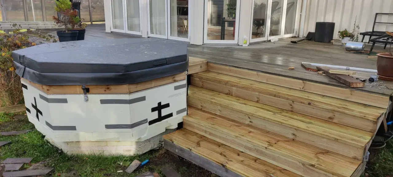 Pågår arbete med att bygga in badtunna i altan. En ny trappa i trä leder upp till altanen.