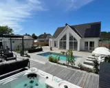 En lyxig pool altan med bubbelpool, solstolar och modernt hus. Perfekt pool altan inspiration för sommaren.