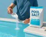 Man häller salt till poolen från en påse "POOL SALT". En liten testare ligger bredvid.
