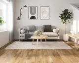 Ljust vardagsrum med grå soffa, runt soffbord och en matta. Golvet är ett vackert laminatgolv med en naturlig träkänsla, där laminatgolv tjocklek bidrar till dess robusthet.