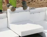 Arbetare lägger isoleringsblock för att gjuta grunden till ett hus.