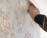 Händer som tapetserar med papperstapet med blomstermönster.