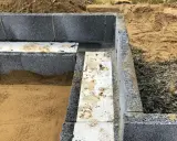 Grunden byggs med lecablock. Sand och grus ligger runt den pågående konstruktionen.