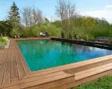 En vacker klorfri pool med trädäck och grönskande omgivning. Perfekt för avkoppling i naturen.