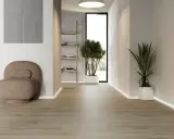 Modern hall med klinker som ger en varm och inbjudande känsla. En bekväm fåtölj och gröna växter skapar en lugn atmosfär.