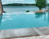 En vacker infinity pool som speglar himlen och omgivande träd. Drömmen om att bygga infinity pool vid en sjö.