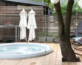 Avslappnad utomhusmiljö med jacuzzi, badrockar och bekväma stolar. Perfekt jacuzzi utomhus inspiration för en lugn stund.