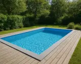 En inbjudande pool med blått vatten, omgiven av en träaltan och grönskande trädgård. Drömmen om att bygga egen pool blir verklighet.