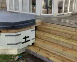 Pågår arbete med att bygga in badtunna i altan. En ny trappa i trä leder upp till altanen.