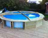 Bygga in rund pool i trädäck. En nybyggd pool med blått vatten omgiven av träpanel.