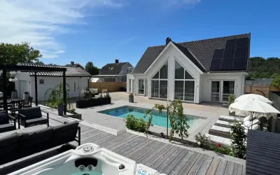En lyxig pool altan med bubbelpool, solstolar och modernt hus. Perfekt pool altan inspiration för sommaren.