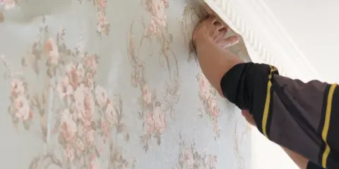 Händer som tapetserar med papperstapet med blomstermönster.