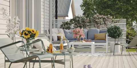 En härlig altan runt huset med bekväma möbler, solrosor och en inbjudande atmosfär för avkoppling.