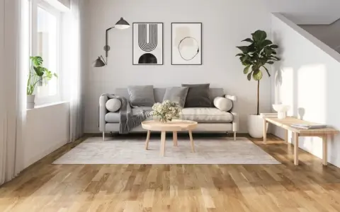 Ljust vardagsrum med grå soffa, runt soffbord och en matta. Golvet är ett vackert laminatgolv med en naturlig träkänsla, där laminatgolv tjocklek bidrar till dess robusthet.