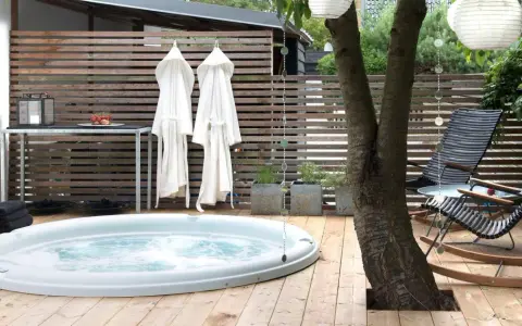 Avslappnad utomhusmiljö med jacuzzi, badrockar och bekväma stolar. Perfekt jacuzzi utomhus inspiration för en lugn stund.