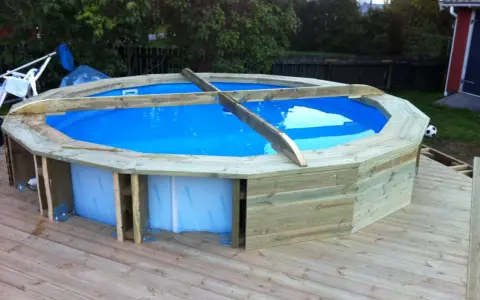 Bygga in rund pool i trädäck. En nybyggd pool med blått vatten omgiven av träpanel.