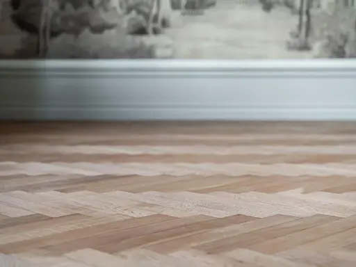 Nyligen slipad fiskbensparkett i ljust trä, redo att förvandla rummet.