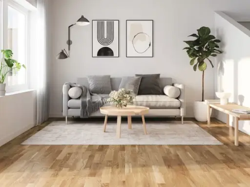 Ljust vardagsrum med grå soffa, runt soffbord och en matta. Golvet är ett vackert laminatgolv med en naturlig träkänsla, där laminatgolv tjocklek bidrar till dess robusthet.