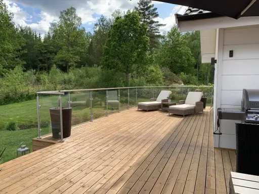 En nybehandlad altan med solstolar och grill, redo för sommarens mys. Snart dags att måla altan för att skydda träet.