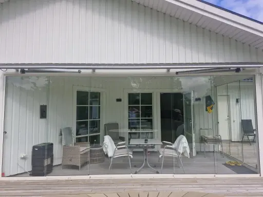 Begagnade glaspartier uterum ger en ljus och öppen känsla. Här syns ett modernt uterum med glasdörrar och fönster.