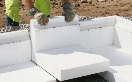 Arbetare lägger isoleringsblock för att gjuta grunden till ett hus.