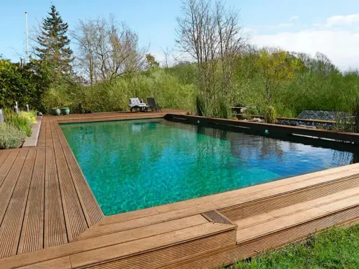 En vacker klorfri pool med trädäck och grönskande omgivning. Perfekt för avkoppling i naturen.