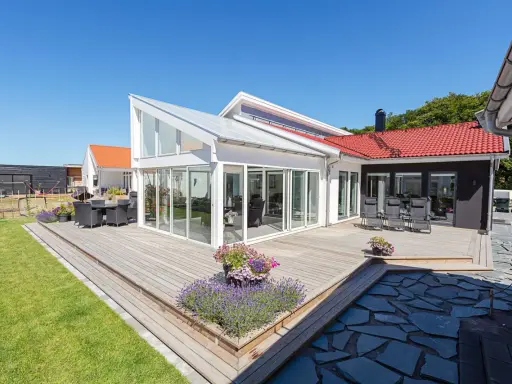 Stor altan med glaspartier och tak, perfekt för sommarkvällar. Kanske krävdes bygglov altan för denna dröm.