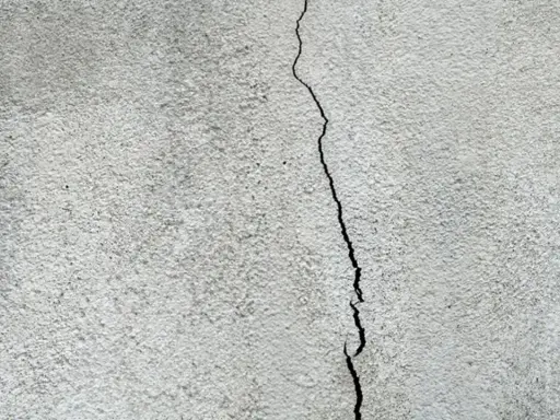En spricka löper genom ett gråspräckligt putsbruk.