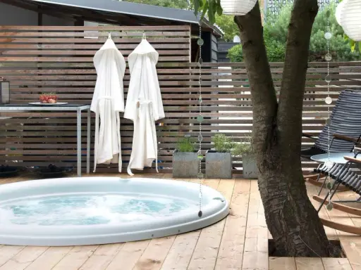Avslappnad utomhusmiljö med jacuzzi, badrockar och bekväma stolar. Perfekt jacuzzi utomhus inspiration för en lugn stund.