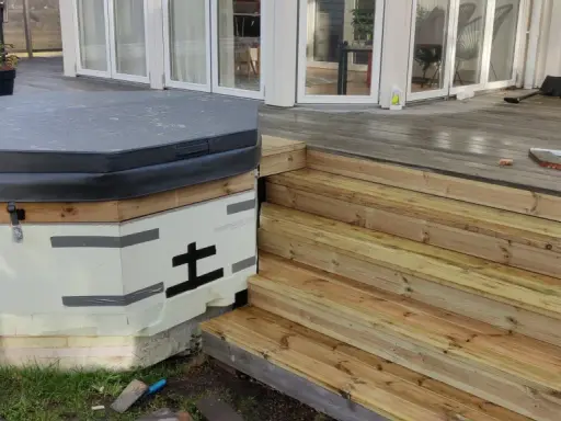 Pågår arbete med att bygga in badtunna i altan. En ny trappa i trä leder upp till altanen.
