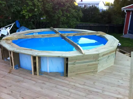Bygga in rund pool i trädäck. En nybyggd pool med blått vatten omgiven av träpanel.