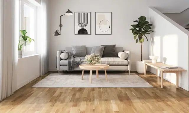 Ljust vardagsrum med grå soffa, runt soffbord och en matta. Golvet är ett vackert laminatgolv med en naturlig träkänsla, där laminatgolv tjocklek bidrar till dess robusthet.