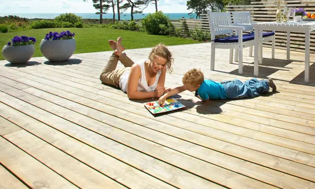 Kvinna och barn spelar spel på en altan med trall tjocklek som ger en stabil yta.