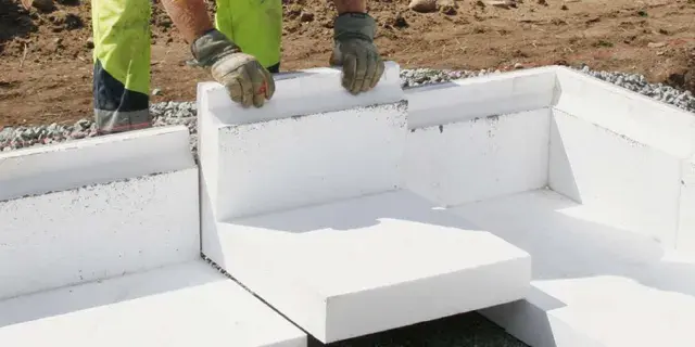 Arbetare lägger isoleringsblock för att gjuta grunden till ett hus.