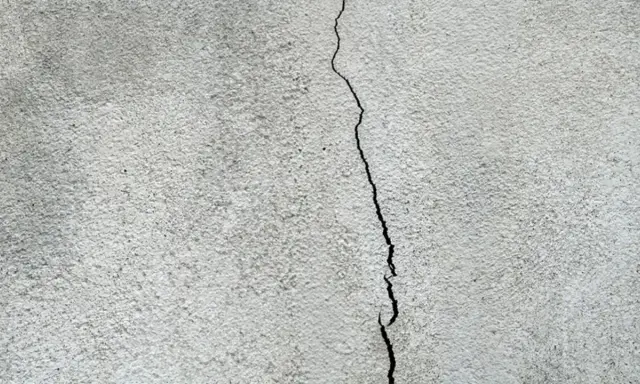 En spricka löper genom ett gråspräckligt putsbruk.