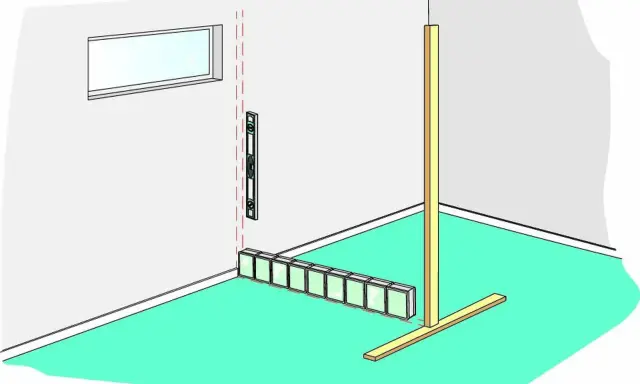 Byggare murar glasblock längs en vägg, med vattenpass och stöd.