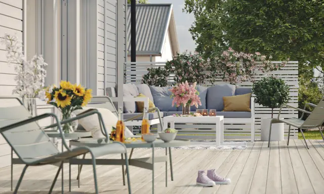 En härlig altan runt huset med bekväma möbler, solrosor och en inbjudande atmosfär för avkoppling.