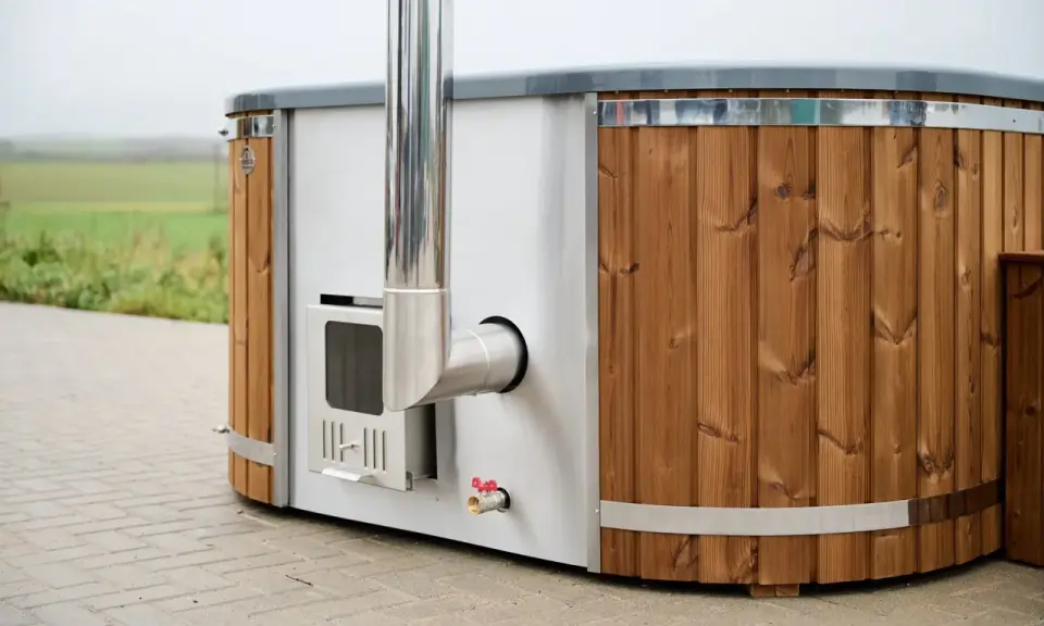 En badtunna hybrid med träpanel och metall, redo för ett avkopplande bad utomhus.