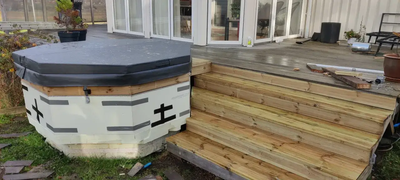 P&aring;g&aring;r arbete med att bygga in badtunna i altan. En ny trappa i tr&auml; leder upp till altanen.