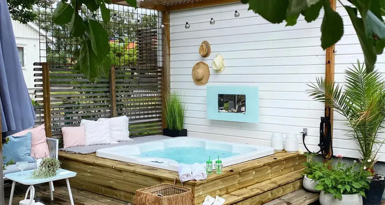 Pool altan inspiration: Ett lyxigt spabad på en träaltan, omgivet av kuddar, växter och en mysig sittgrupp. Perfekt för avkoppling.