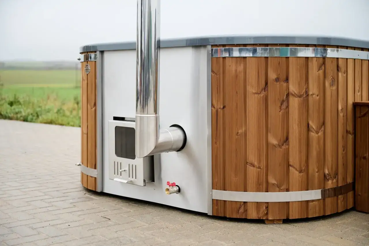 En modern badtunna hybrid med tr&auml;panel och integrerad eldstad. Perfekt f&ouml;r avkoppling utomhus.