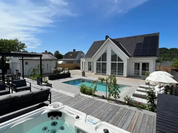 En lyxig pool altan med bubbelpool, solstolar och modernt hus. Perfekt pool altan inspiration för sommaren.