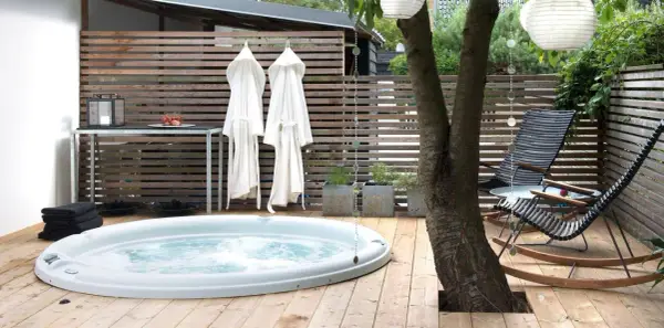 Avslappnad utomhusmiljö med jacuzzi, badrockar och bekväma stolar. Perfekt jacuzzi utomhus inspiration för en lugn stund.